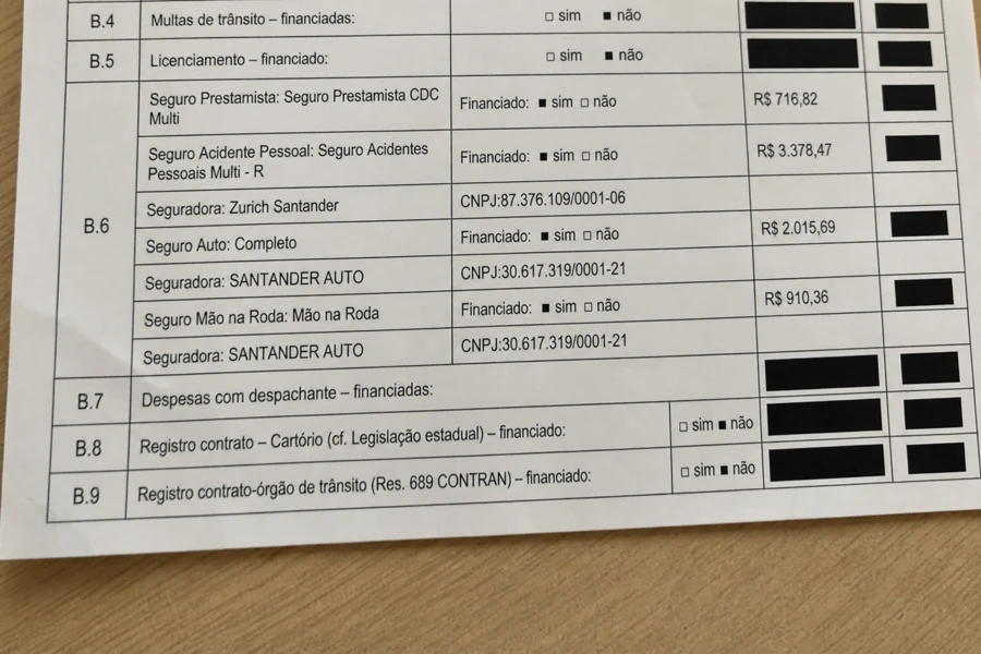 Foto ilustrativa de celular, com contrato sobre a mesa, leves amassados e foco nos seguros da cláusula B.6